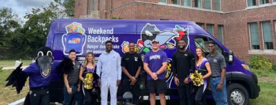- Weekend Backpacks Baltimore Ravens players, cheerleaders, and mascot in front of the Weekend Backpacks' van